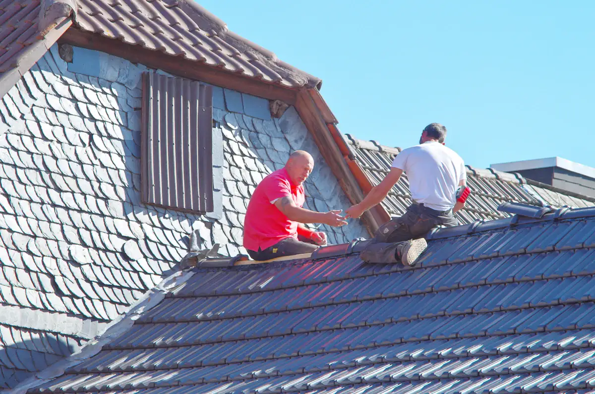 Dva pokrývači při opravě střešní krytiny